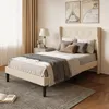 A bedroom scene featuring a bed with pillows and a blanket, a bedside table with a lamp, and artwork on the wall. Produktbild-Vorschau