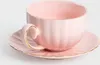 A pink teacup and saucer with gold trim on a white background. Produktbild-Vorschau