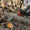 A person is using a chainsaw to cut a log that is supported by a sawhorse. The background is filled with a large pile of cut logs. Anteprima dell’immagine prodotto
