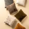 Several fluffy square cushions are arranged on a light beige surface. Produktbild-Vorschau