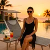 A woman relaxing on a lounge chair by a pool at sunset. Produktbild-Vorschau