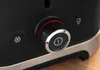 A close-up view of the control panel of a black toaster, showing a dial with settings and two buttons. Voir les images du produit