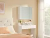 A bedroom scene with a white vanity and a mirrored cabinet above it, next to a bed. Produktbild-Vorschau