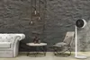 A modern living room scene featuring a sofa, coffee table, chair, and a floor fan against a textured gray wall. Anteprima dell’immagine prodotto