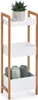 A three-tiered storage shelf made of bamboo and white MDF, with a potted plant on the top shelf and rolled towels on the bottom shelf. Náhľad obrázku produktu