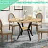 A round wooden dining table with black metal legs and a shelf, surrounded by four upholstered chairs in a dining room setting. Produktbild-Vorschau