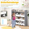 A young child is holding a stuffed animal in front of a gray toy storage unit filled with toys and books. Podgląd zdjęcia produktu