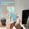 A person holding a clear smartphone case with a Samsung Galaxy A13/A13 5G phone inside, with a laptop and a potted plant in the background. Produktbild-Vorschau