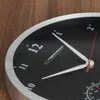 Close-up of a black wall clock with silver trim, showing the clock face and hands. Podgląd zdjęcia produktu