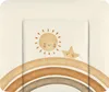 A close-up view of a baby changing mat with a watercolor-style print of a sun, a star, and a rainbow. Produktbild-Vorschau