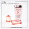 A pink bottle of Kerastase Genesis shampoo is displayed with two red acrylic blocks, against a white background. Text overlays provide product information. Produktbild-Vorschau