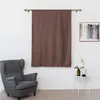 A living room scene with a gray armchair, a brown curtain, and a small side table with decorations. Náhled obrázku produktu