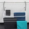 A white foldable drying rack with four bars, hanging on a white radiator. It has four towels draped over the bars: one dark gray, one blue, one dark gray, and one teal. Podgląd zdjęcia produktu