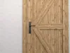 A close-up view of a wooden door with a black metal handle. Produktbild-Vorschau