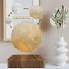 A levitating moon lamp is displayed on a wooden base, with graphics showing different light settings. Náhled obrázku produktu