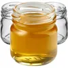Three small glass jars, one filled with a golden liquid, are arranged on a white background. Podgląd zdjęcia produktu