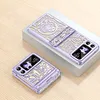 Two purple phone cases with intricate designs are displayed on a light gray box and a wooden surface. Produktbild-Vorschau