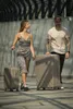 A man and a woman are walking with luggage. Produktbild-Vorschau
