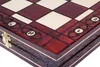 A close-up view of a wooden chessboard, showing the edge with inlaid letters and decorative patterns. Produktbild-Vorschau