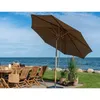 An outdoor patio setting with a table, chairs, and a large umbrella near the ocean. Voir les images du produit