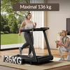 A woman is running on a treadmill in a living room, with another woman watching and clapping. There is a large window showing a garden outside. Produktbild-Vorschau