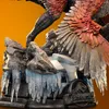 A close-up of a dinosaur statue's base, featuring rocks, ice, and a Jurassic World logo. Podgląd zdjęcia produktu