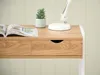 A close-up view of a wooden desk with a drawer and a small plant. Voir les images du produit