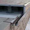 Close-up view of a drainage profile system installed along a brick wall and a raised deck. Produktbild-Vorschau