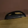 A close-up view of a black handle attached to a brown fabric surface, resting on a wooden surface. Produktbild-Vorschau