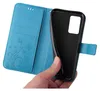 A hand is holding a blue flip phone case, showing the inside with card slots and floral pattern, and the black phone holder. Produktbild-Vorschau