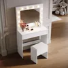 A white vanity table with a lighted mirror and a stool in a room. Voir les images du produit