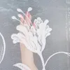 A hand with pink nail polish is shown behind a white lace curtain with a floral pattern. Produktbild-Vorschau