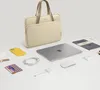 A beige laptop bag with accessories laid out around it. Náhľad obrázku produktu