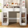 A white vanity table with a lighted mirror and shelves filled with makeup and accessories. Voir les images du produit