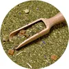 A close-up view of yerba mate tea leaves with a wooden scoop and some dried fruit pieces. Produktbild-Vorschau