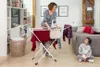 A woman is hanging laundry on a drying rack in a living room, while a boy sits on the floor reading a book. Náhľad obrázku produktu
