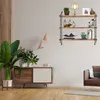 A living room scene with a wooden cabinet, a large plant, and a three-tiered shelf unit mounted on the wall. Produktbild-Vorschau