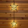 Two star-shaped string lights hang vertically against a wooden plank wall. Voir les images du produit