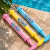 Drei bunte Wasserpistolen, Pink, Gelb und Blau, mit der Aufschrift 'FIREWORKS WATER GUN', auf einer nassen Steinoberfläche platziert Produktbild-Vorschau
