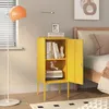 A yellow nightstand with an open door, filled with books and decorative items, placed next to a bed. Podgląd zdjęcia produktu