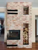 A brick fireplace with a built-in wood-burning stove and shelves. Produktbild-Vorschau