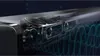 A close-up, detailed view of a soundbar's internal speaker components, with stylized sound waves emanating from it. Produktbild-Vorschau