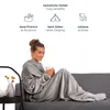 A woman sitting on a couch, wrapped in a gray blanket with sleeves, holding a mug. Anteprima dell’immagine prodotto