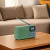 A green DAB radio is placed on a wooden table in front of a couch. Produktbild-Vorschau