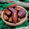 A close-up of dates in a bowl, surrounded by green moss and branches. Voir les images du produit