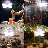 Collage of four images showing a foldable LED solar lamp in different settings: camping, a food stall, an indoor event, and an outdoor patio. Anteprima dell’immagine prodotto