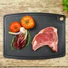 A raw beef steak and vegetables are arranged on a black cutting board, which is placed on a distressed wooden surface. Anteprima dell’immagine prodotto
