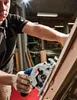 A person is using a circular saw to cut wood in a workshop. Voir les images du produit