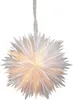 A white paper star lantern with perforations, lit from within, hanging from a ribbon. Podgląd zdjęcia produktu