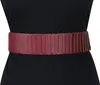 A close-up of a burgundy elastic belt worn around a black dress. Produktbild-Vorschau
